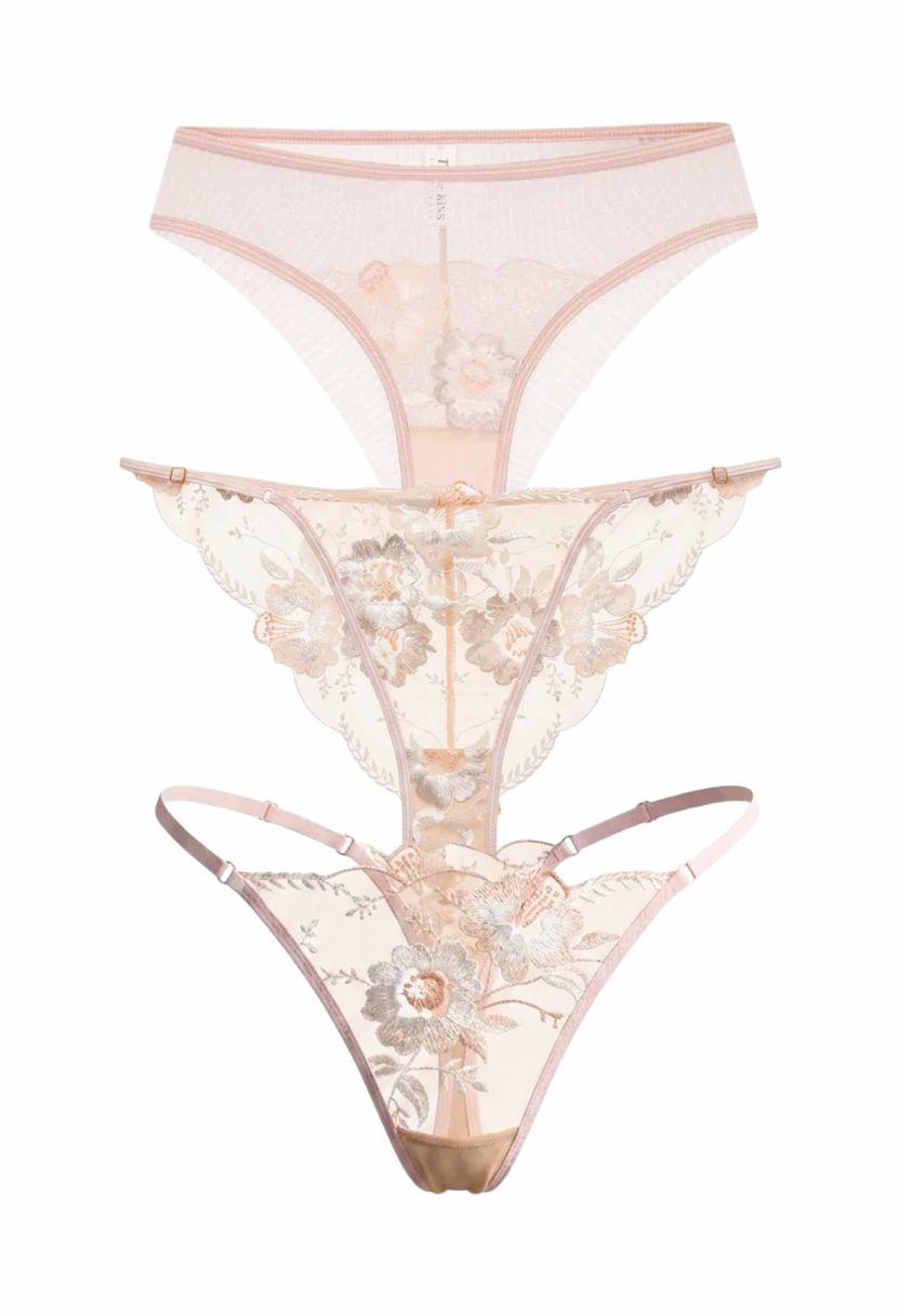 Three pairs of sheer lace and mesh thong panties in soft blush pink tones, stacked vertically on a plain white background. The bottom pair features prominent floral lace applique and a central bead detail.