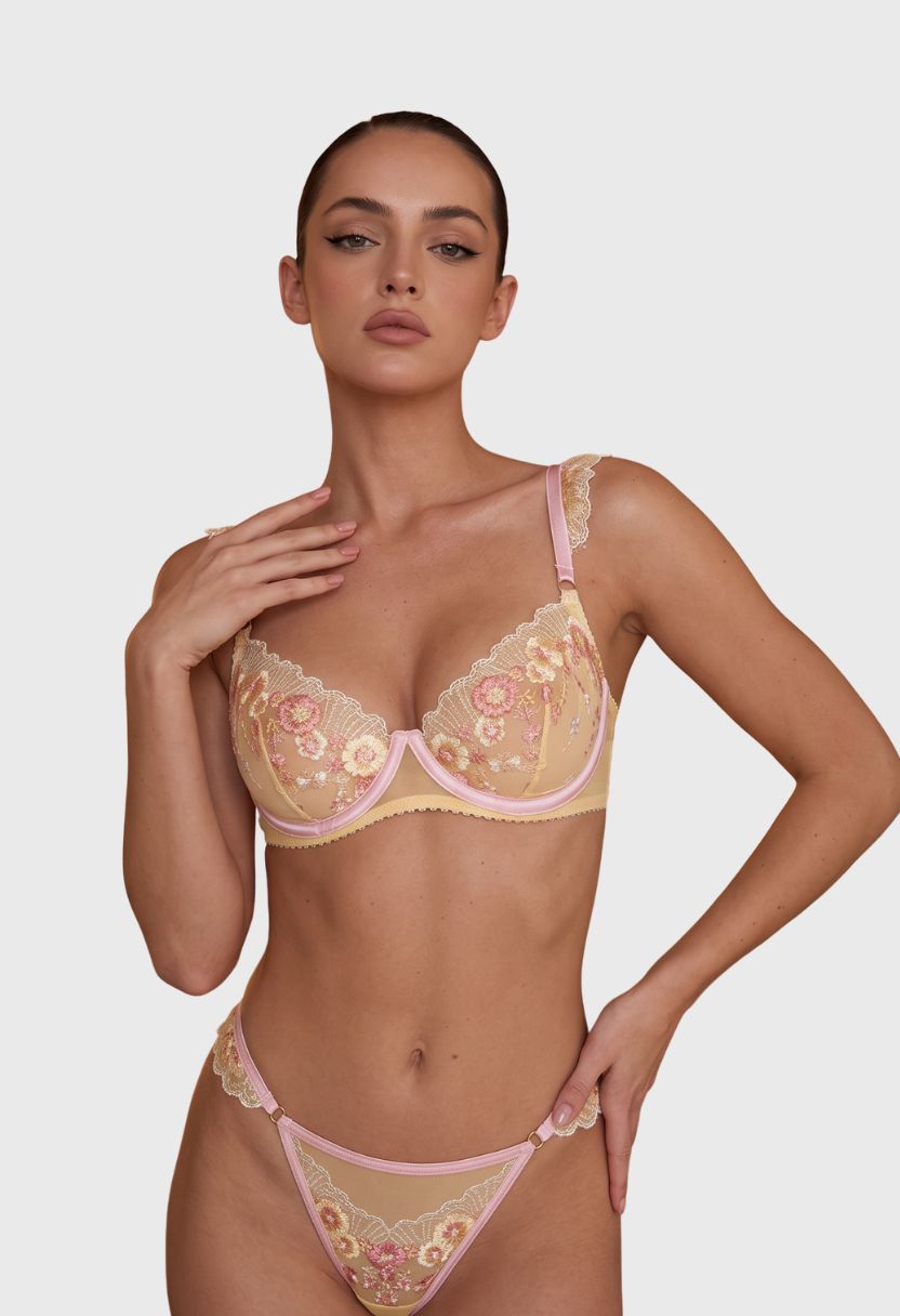 Sylvie butter yellow embroidered mesh bra and thong set on model, front view. A woman modeling a two-piece lingerie set featuring a beige and pink floral lace bra and matching panties against a light gray studio background.